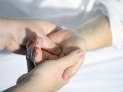 Nahaufnahme auf Hände einer Therapeutin, die eine Hand einer Patientin hält